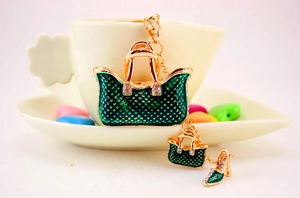 Macro detail of dark green handbag keychain with gold trim and rhinestone shoe charm