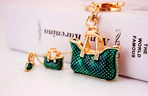 Detail of gold metal keychain featuring green enamel handbags and high heel with rhinestones