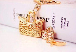 Detail of a golden handbag keychain with a tiny stiletto shoe and sparkling rhinestone accents