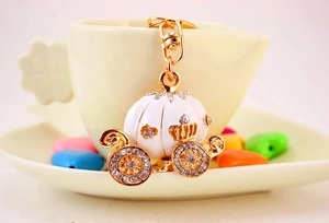 Exquisite white enamel pumpkin carriage keychain with rhinestones hanging on a cup