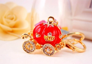 Macro shot of red enamel pumpkin carriage keychain with gold finish and white rhinestones