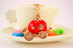 Close-up of a red pumpkin carriage keychain with rhinestones on a coffee cup edge