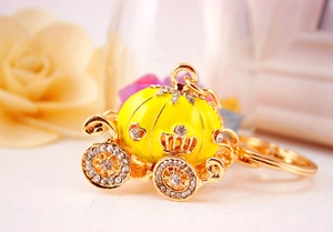 Detailed view of yellow enamel pumpkin carriage keychain with gold finish and white crystals