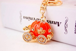Macro view of gold pumpkin carriage keychain with orange enamel and sparkling rhinestones