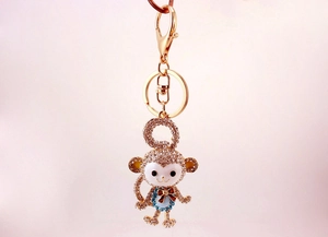 Detailed view of crystal-encrusted monkey keychain with blue outfit and red bow