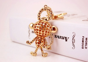 Close-up of golden hollow heart monkey keychain with articulated limbs on a book