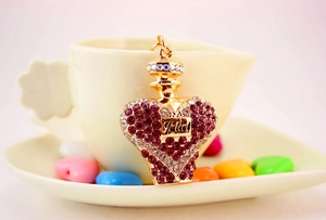 Close-up of golden perfume bottle keychain with Juliet script and pink crystals