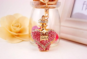 Detail of a golden heart perfume bottle keychain with pink crystals and Juliet text