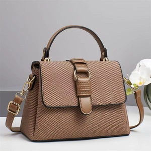 Brown woven texture handbag with leather straps and gold ring buckle in a minimalist setting