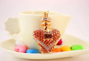 Detail of crystal perfume bottle keychain with orange rhinestones on a mini teacup