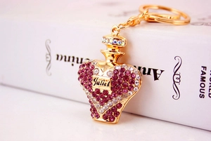 Close-up of golden perfume bottle keychain with purple rhinestones and Juliet engraving