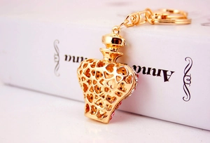 Detailed view of a golden perfume bottle keychain with red rhinestones and heart patterns