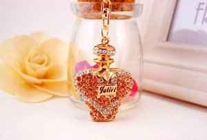 Macro shot of heart perfume bottle keychain with orange crystals and gold finish