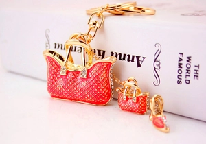 Macro shot of rose pink rhinestone handbag and high heel pendants on a golden keychain