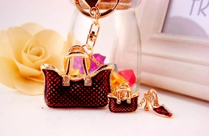 Close-up of red quilted handbag and high heel metal charms on a golden keychain