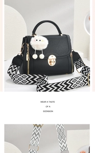Detail showing litchi texture black handbag with a patterned strap and plush charm