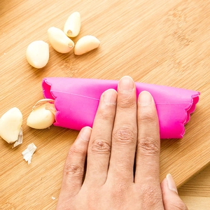 Éplucheur d'ail en silicone rose sur planche en bois pour éplucher facilement en cuisine