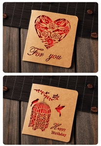 Close-up of vintage kraft cards with heart and birdcage laser-cut designs on wood