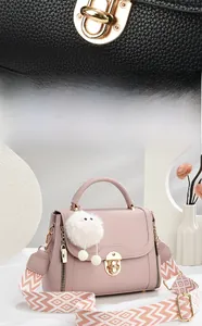 Detail of elegant litchi grain leather handbag with gold twist lock and plush charm