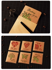 Flat lay of vintage kraft paper cards with cutout designs, envelopes, and pen on dark wood