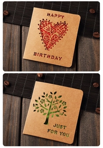 Detail of vintage kraft paper cards with cutout heart and tree designs on wood table