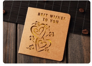 Detail of vintage kraft paper card with hollow heart pattern on dark wood background