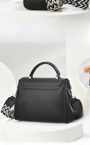 Detail view of black litchi pattern leather handbag with geometric embroidery strap