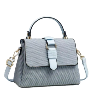 Elegant light blue woven handbag for women with gold circular buckle on white background