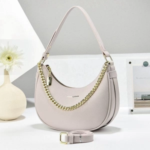 Détail du sac croissant rose à grain de litchi avec chaîne dorée et lettrage