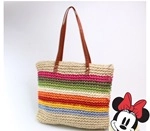 Detail of multi-color striped straw woven tote bag with brown faux leather handles