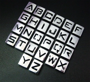 Macro shot of polished 8mm silver zinc alloy square A-Z alphabet loose beads
