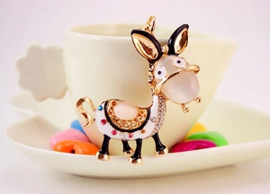 Macro shot of cute cartoon donkey keychain with pink cat eye stone and sparkling crystals