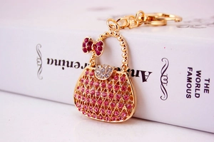 Dettaglio macro del portachiavi a borsa con strass rosa e fiocco di cristallo viola
