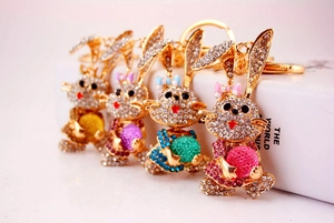 Detail view of four rhinestone bunny keychains holding colorful orbs in gold finish
