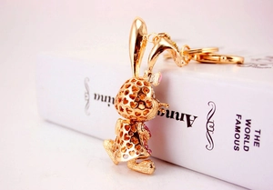 Detailed view of golden heart-shaped bunny keychain with pink rhinestones on a book