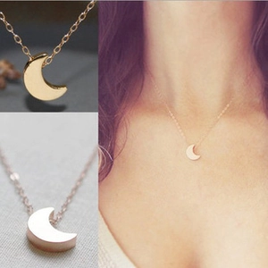 Detailed view of crescent moon pendant necklace in gold and rose gold on a model