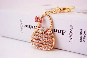 Detail of golden handbag keychain with pink bow and sparkling rhinestones on book