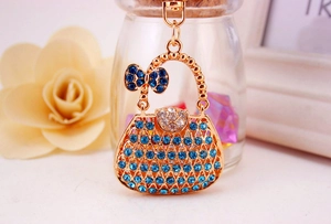 Close-up of golden handbag keychain with blue and clear rhinestones and bow detail