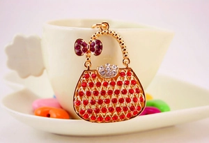 Close-up of golden handbag charm encrusted with red and clear crystals on metal base