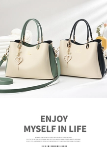 Detailansicht der cremefarbenen Lederhandtasche mit Goldbeschlägen und Perlenanhänger