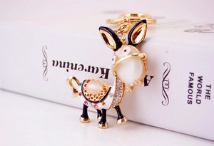 Detail of cute donkey keychain with rhinestones and cat-eye stones on a golden base