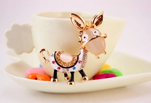 Detail of cartoon donkey brooch with pink opal and colorful rhinestones on a coffee cup