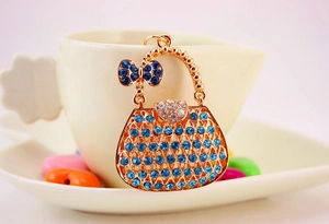Detail of gold handbag keychain featuring blue rhinestones and crystal bow decoration