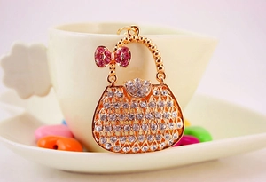 Detail of a gold handbag keychain with crystal rhinestones and a pink bow on a cup