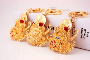 Detailansicht von drei goldenen Kröten-Schlüsselanhängern mit Strass und Glücksmünzen