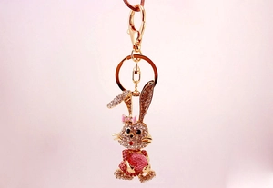 Detailed view of rhinestone bunny keychain in gold metal with pink crystal accents