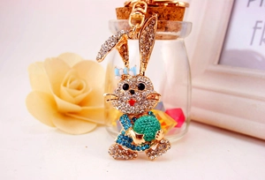 Macro detail of a sparkling rhinestone bunny keychain featuring blue dress and green ball