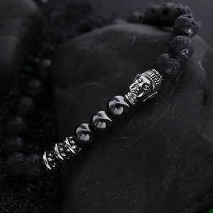 Lava rock and hematite beaded bracelet with silver buddha head on black stone background