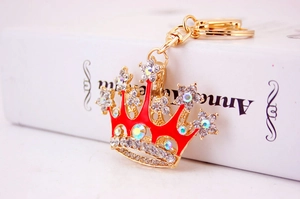 Detail of a golden crown keychain with red enamel and sparkling rhinestones on a book
