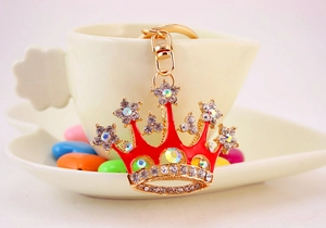 Macro detail of golden crown keychain with red enamel and sparkling crystal rhinestones